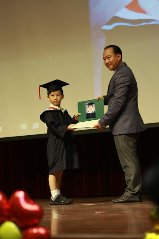 Mr Taing presenting the scroll to a graduate.